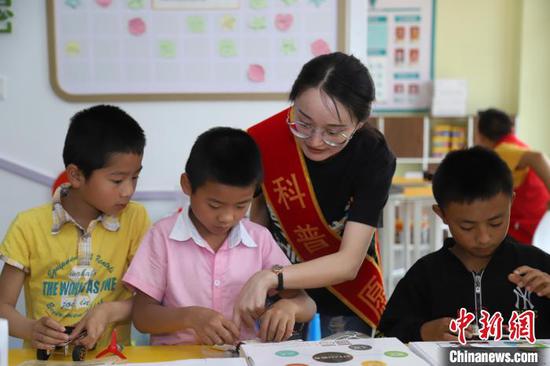 图为科普志愿者指导孩子制作手工模型。 岳旺 摄 图为科普志愿者指导孩子制作手工模型。 岳旺 摄
