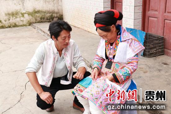 李红(左)在跟绣女讨论苗绣 。