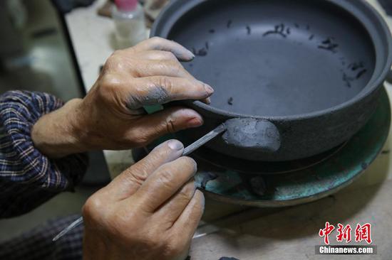 胡正德将“黑砂陶”器具塑形。中新社记者 瞿宏伦 摄