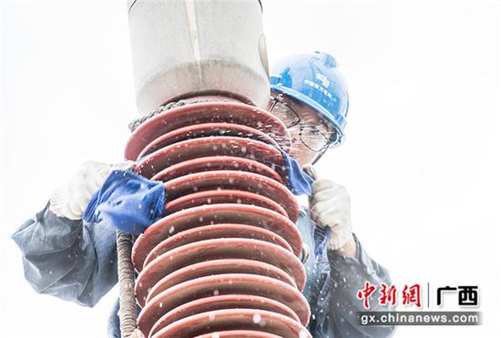 8月12日,南方电网广西梧州供电局作业员莫佳林扎着安全绳索,爬到220千伏苍梧变电站大型变压器顶部,用湿布擦拭绝缘套管上的污渍。何华文 摄 8月12日,南方电网广西梧州供电局作业员莫佳林扎着安全绳索,爬到220千伏苍梧变电站大型变压器顶部,用湿布擦拭绝缘套管上的污渍。何华文 摄