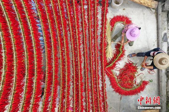 村民在贵州省毕节市大方县羊场镇陇公村整理晾晒编好的辣椒。 罗大富 摄