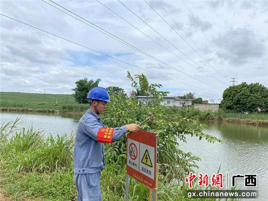 志愿者在鱼塘边设置“高压线下禁止垂钓”的宣传牌。沈东升 摄 广西崇左志愿者深入田间地头宣传涉电公共安全