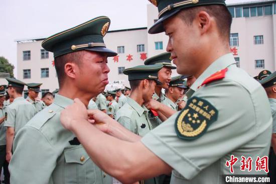 图为一名战友为退伍老兵卸警衔。 武警贵州总队机动支队供图 图为一名战友为退伍老兵卸警衔。 武警贵州总队机动支队供图