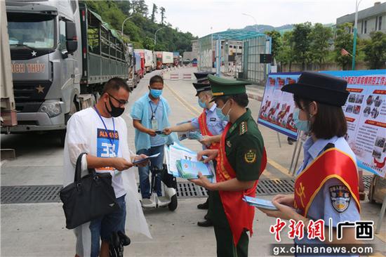 图为民警向出入境司机发放宣传手册 图为民警向出入境司机发放宣传手册