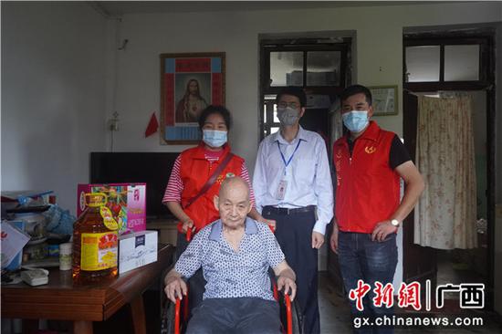 志愿者扶老人坐上轮椅 广西爱心企业协手志愿者开展慈善捐赠活动