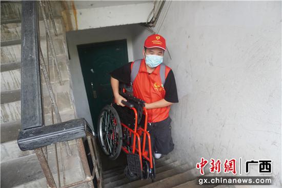 志愿者搬轮椅上楼 广西爱心企业协手志愿者开展慈善捐赠活动