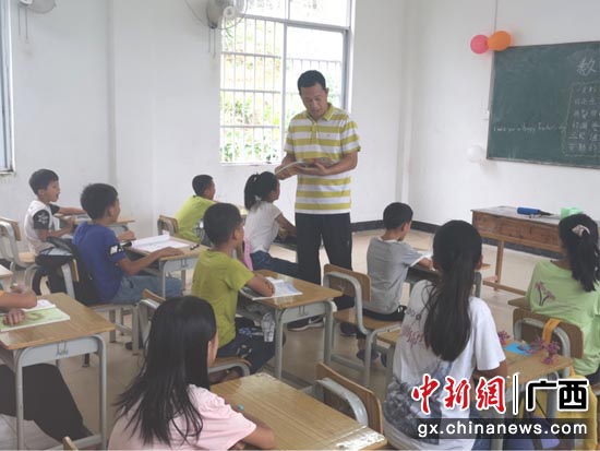 南宁师范大学驻村第一书记磨有积在给学生上课。 黄光荣 摄 广西宁明县鲜花献给最美乡村教师