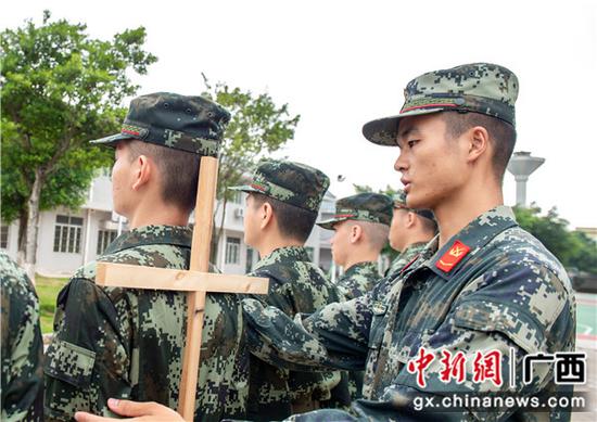 一名班长在用十字架帮助新兵克服驼背问题。 一名班长在用十字架帮助新兵克服驼背问题。