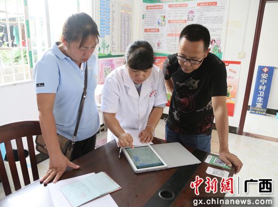 融安县医保局工作人员了解医保即时结算系统在村卫生室的实际使用情况。罗洁芳 摄