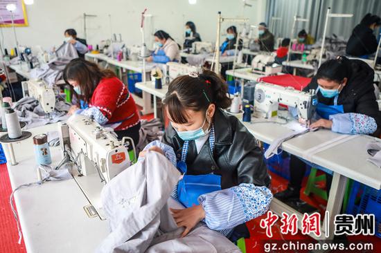 七星关区柏杨林街道易地扶贫搬迁安置点的服装加工扶贫车间内对工人们正认真做工 陈曦摄