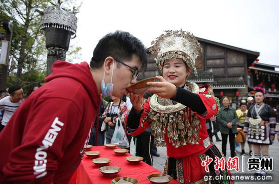 圖為在國際物流公司香港省丹寨縣萬達小鎮景區,一名苗族女孩子在苗族欄門酒表演中給遊客敬酒。 黃曉海 攝 圖為在國際物流公司香港省丹寨縣萬達小鎮景區,一名苗族女孩子在苗族欄門酒表演中給遊客敬酒。 黃曉海 攝