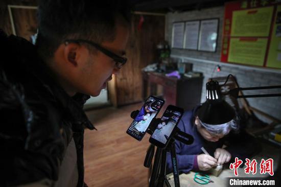 10月10日，银匠潘仕学在麻料村通过短视频平台直播银饰制作过程。　瞿宏伦 摄