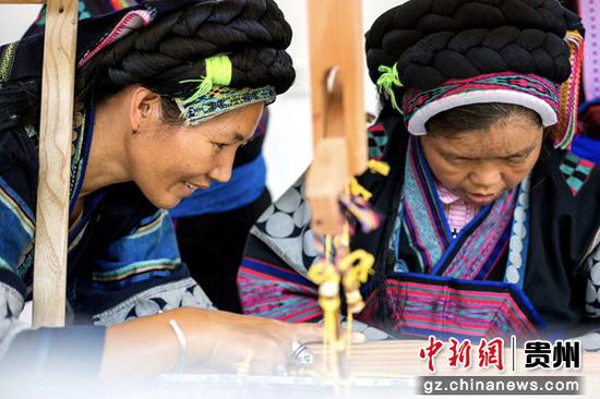 圖為伍德芬(左)在手把手給鄉親傳授織錦技能 圖為伍德芬(左)在手把手給鄉親傳授織錦技能