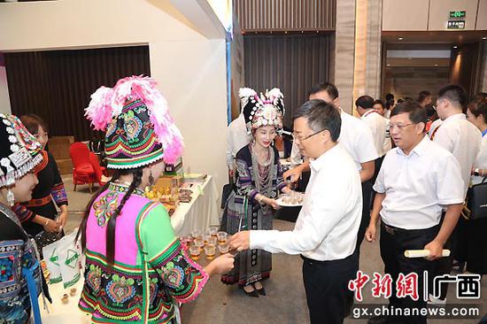 在2020年定点扶贫县消费扶贫现场推进会直播产品展示厅里,广西隆林各族自治县少数民族讲解员向总行党委委员、副行长徐一丁、广西区分行纪委书记、党委委员夏建光介绍扶贫产品。