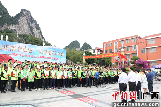 图为覃生贤与驻村干部交流