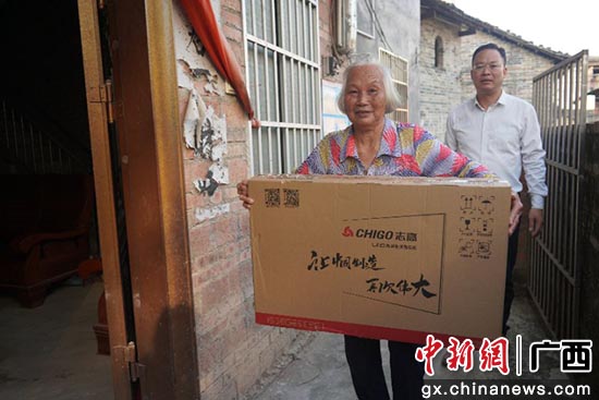 钦北区结对帮扶联系干部将商会捐赠的电视机送到贫困户家。
