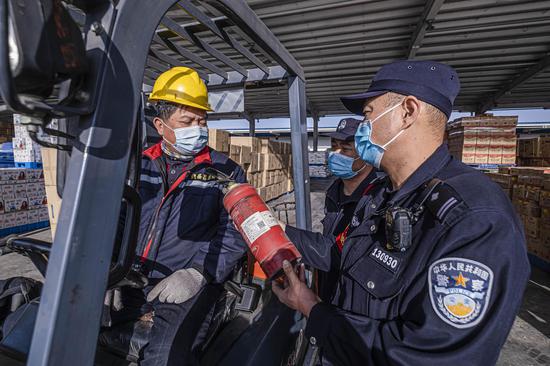 民警对日用货区装卸车辆消防器材进行检查。