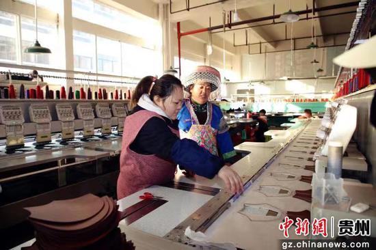 图为王信梅(右一)向公司职工指导苗绣制作技艺 图为王信梅(右一)向公司职工指导苗绣制作技艺