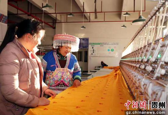 图为王信梅（右一）向公司职工指导苗绣制作技艺