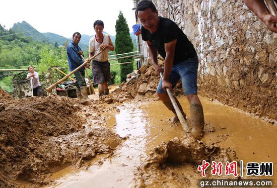 花溪乡借魁村第一书记徐伟（前）帮助受灾农户清理泥土。