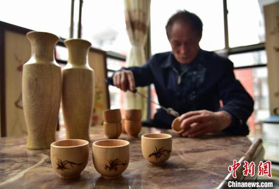 吴明章在为好友制作的木质茶杯进行免费的烙画创作。 杨武魁 摄