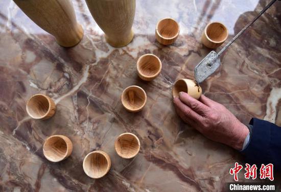 吴明章在为好友制作的木质茶杯进行免费的烙画创作。 杨露婷 摄