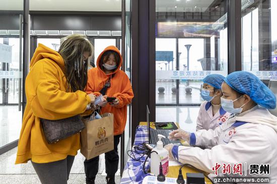 2020年12月15日,黔西高铁站工作人员对旅客进行疫情防控检测。