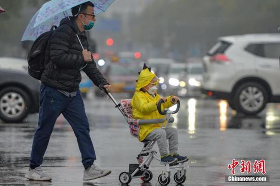 资料图:市民冒雨出行。 中新社记者 田雨昊 摄