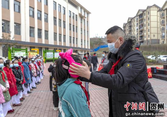 在锦绣学校教学楼前举行送温暖仪式，老师为学生戴上冬季护具。