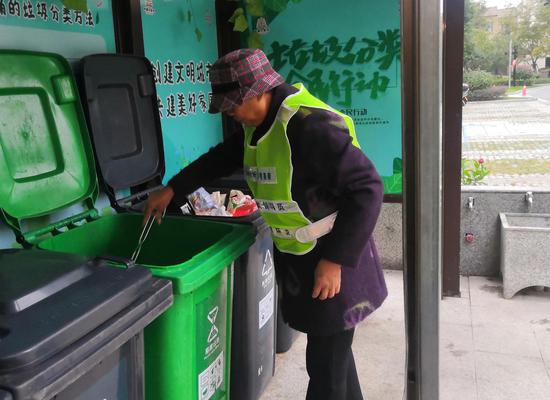 胡赛娥对居民投放的垃圾进行二次分类。金华开发区垃圾分类办提供