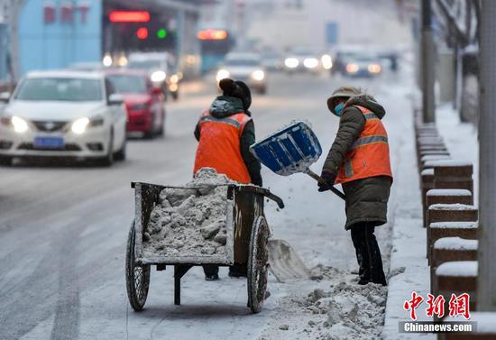 图为环卫工人清理道路积雪。 中新社记者 刘新 摄