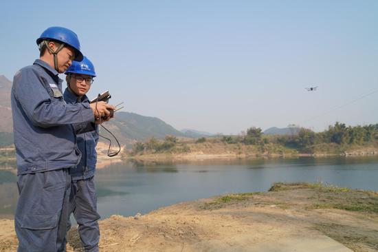在柳城县凤山镇，南方电网广西柳州柳城供电局员工使用无人机对10千伏跨江供电线路进行巡视。 马聪 摄