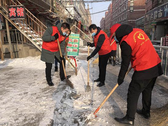 志愿者齐心协力地清理着路面上的积冰。