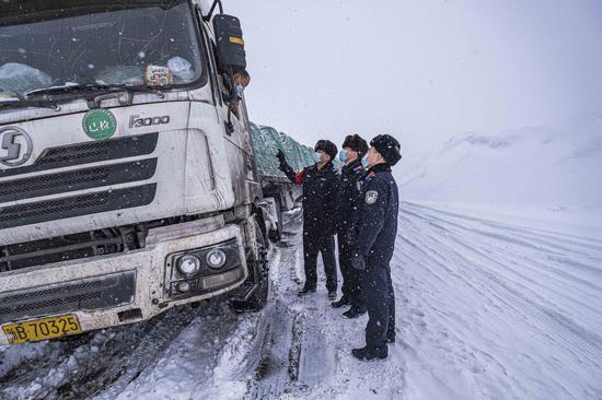 民警在巡线途中询问因大雪深陷雪中货车司机情况。
