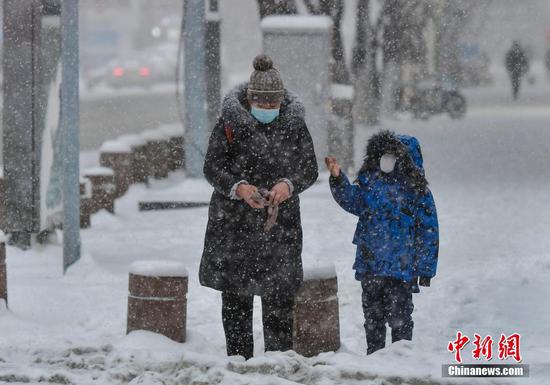 1月23日，新疆乌鲁木齐市迎来一场强降雪天气，民众冒雪外出。 中新社记者 刘新 摄