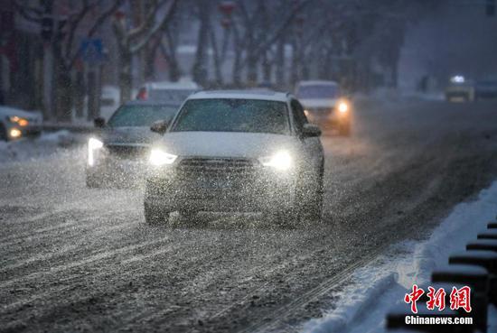 1月23日，新疆乌鲁木齐市迎来一场强降雪天气，车辆在湿滑道路上打开车灯缓慢行驶。乌鲁木齐气象台1月23日10时41分发布暴雪黄色预警信号。 中新社记者 刘新 摄
