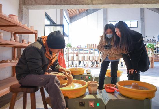 两位游客在五四村一家陶瓷工坊观看陶瓷制作。王刚 摄