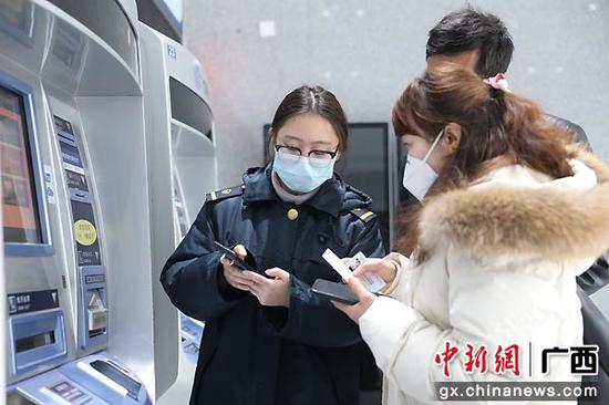 图为桂林站客运工作人员耐心指导旅客如何注册并提取健康码。郑长贤 摄