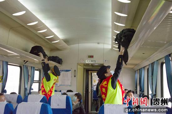贵阳客运段志愿者在车厢内为旅客放行李。