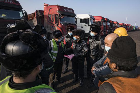 民警在煤矿作业车辆停留场向工人师傅讲解电信诈骗的常用手段。
