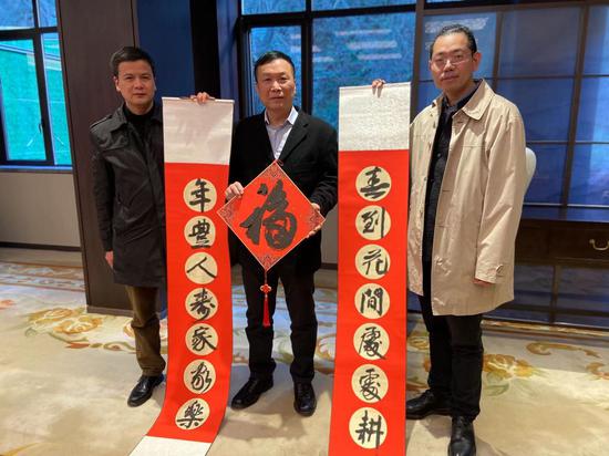 　　大陆书法家梁文斌（右）与绍兴市台办主任石剑晗（左）向台商张金满（中间）送春联、送福字。 项菁供图