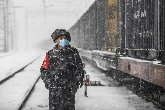 民警冒雪对编组场待发货运列车进行安全巡查。