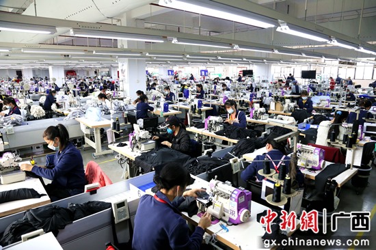 广西宁泰服装有限公司的生产车间内工人正在工作岗位上紧张作业 潘志安 摄