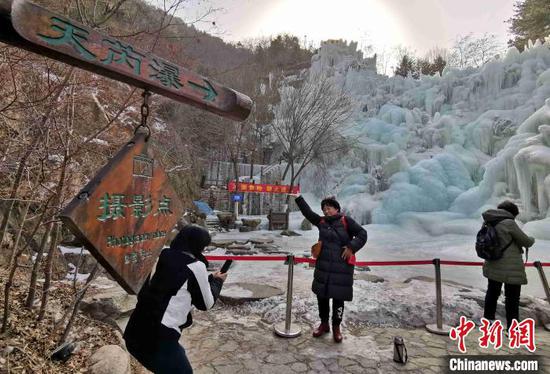 图为游客在九如山风景区的冰瀑前游赏拍照。　赵晓 摄