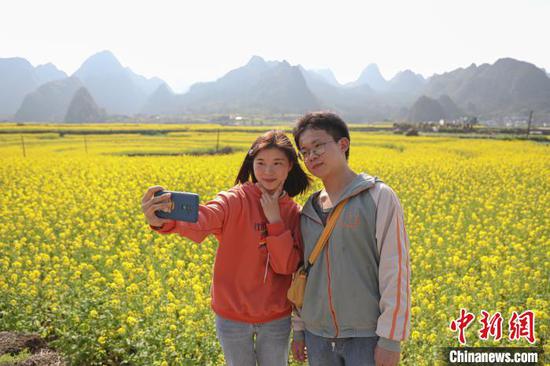2月23日，游客在贵州万峰林油菜花田里自拍。　瞿宏伦 摄