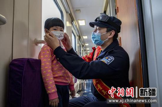 乘警王永江在Z69次列车车厢内帮助小旅客戴口罩。