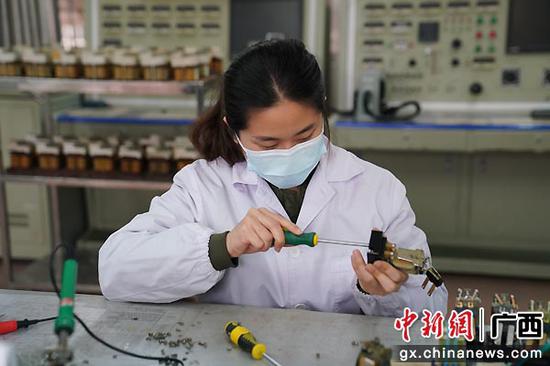 图为南宁检修车间综合工区职工黄琪正在作业台前检修灯丝转换继电器设备。