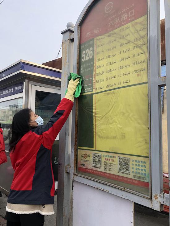 志愿者擦拭公交站牌。