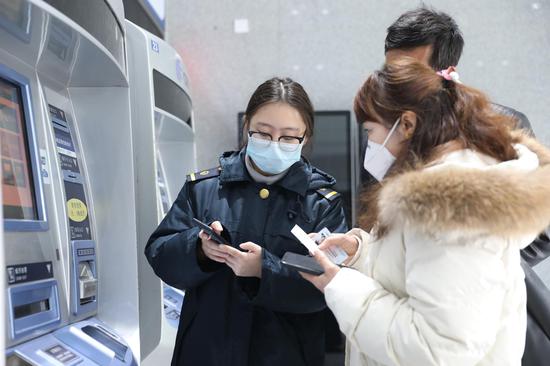 桂林火车站客运工作人员耐心指导旅客如何注册并提取健康码。郑长贤 摄