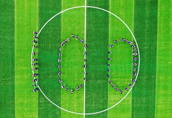埭溪镇上强中学学生手捧绿植在学校操场上摆成100字样队形。何伟卫 摄